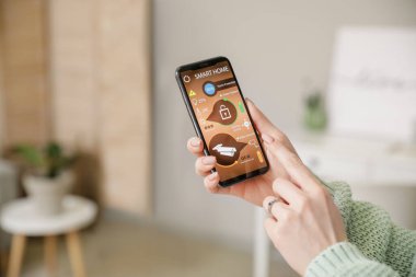 Akıllı ev güvenlik sistemi uygulaması kullanan cep telefonu olan kadın, kapat