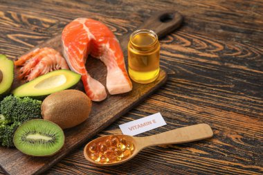 E vitamini ve ahşap arka planda balık yağı kapsülleri açısından zengin ürünlere sahip tahta, yakın plan.