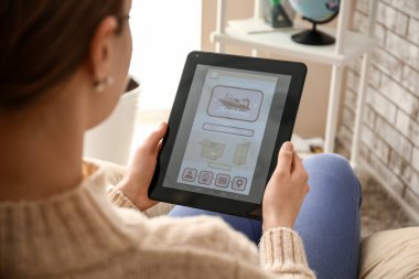 Evde elinde tablet bilgisayarı olan bir kadın teslimat hizmeti başvurusunun açık sayfasını tutuyor.