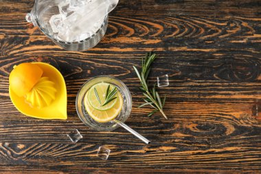 Bir bardak sağlıklı limonata ve ahşap arka planda sıkma.