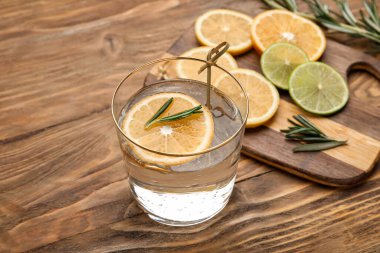 Bir bardak sağlıklı limonata ve ahşap arka planda turunçgil meyvesi.