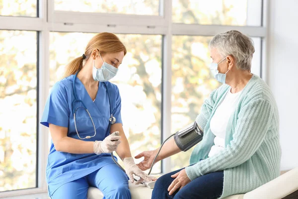 Doctor Measuring Blood Pressure Senior Woman Clinic — Stock Photo, Image