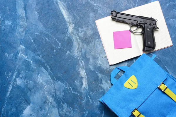 带彩色背景笔记本的手枪和背包 学校枪击案概念 — 图库照片