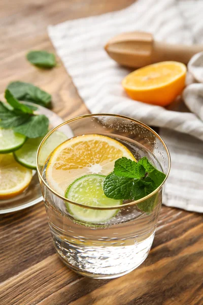 Bir bardak sağlıklı limonata ve ahşap arka planda turunçgil meyvesi.