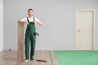 Marangoz, odaya lamine döşeme montajı sırasında baş parmağını kaldırdığını gösteriyor