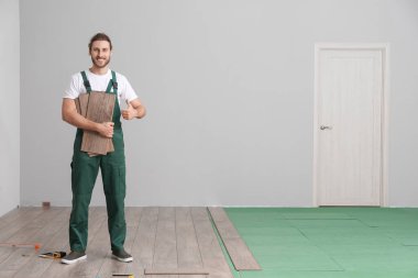 Kaplama numuneli marangoz odada parmak uçlarını gösteriyor.