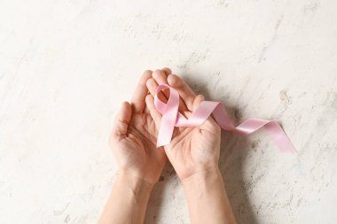 Açık arkaplanda pembe kurdeleli erkek eller. Göğüs kanseri kavramı