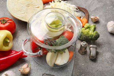 Arkaplanda taze sebzeler olan şık bir tencere.