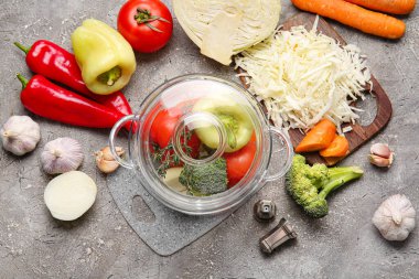 Arkaplanda taze sebzeler olan şık bir tencere.