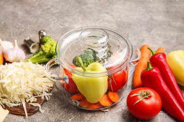 Arkaplanda taze sebzeler olan şık bir tencere.