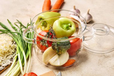 Hafif arka planda taze sebzeli, şık bir tencere.