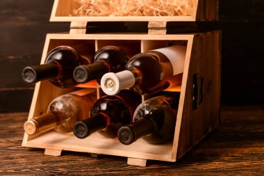 Ahşap arka planda şarap şişeleri olan bir kutu.