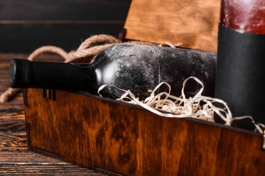 Ahşap arka planda şarap şişeleri olan bir kutu, yakın plan.