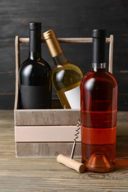 İçinde şarap şişeleri ve ahşap arka planda tirbuşon olan bir kutu.