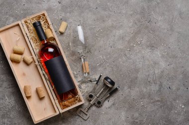Arkaplanda şarap, cam ve tirbuşon dolu bir kutu.