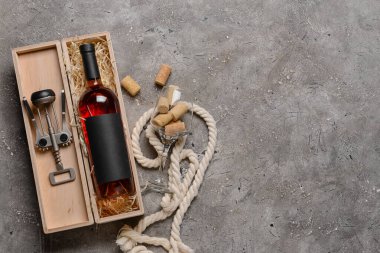 Bir şişe şarap, tirbuşon ve arka planda cam.