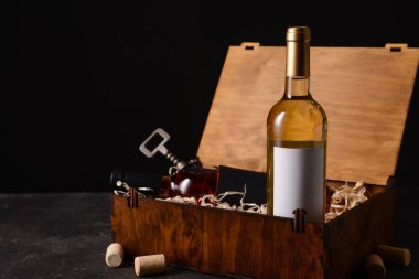 Arka planda şarap, cam ve tirbuşon şişeleri olan bir kutu.