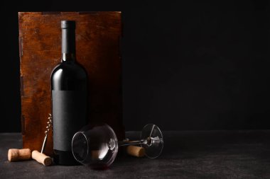 Arka planda şarap, cam ve tirbuşon dolu bir kutu.