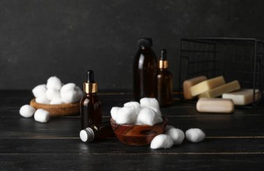 Yumuşak pamuklu kase ve koyu arkaplanda farklı kozmetik şişeler