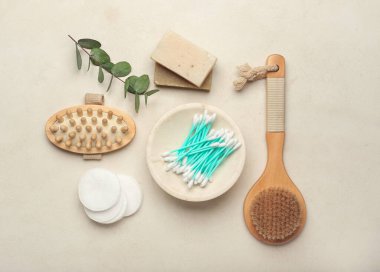 Hafif arkaplanda pamuk çubukları, tarak, fırça, sabun ve tomurcuklarla kompozisyon