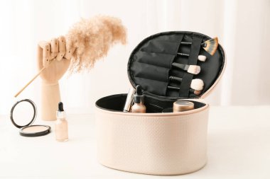 Dekoratif kozmetik ürünleri olan şık bir çanta ve hafif arka planda tahta el.