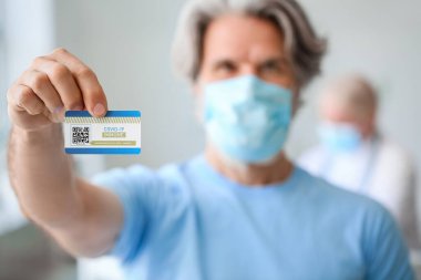 Klinikte aşı kartı olan yaşlı bir adam.