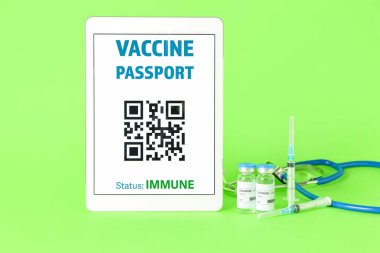 Tablet bilgisayar ekranında elektronik bağışıklık pasaportu ve renkli arkaplanda covid-19 aşısı.