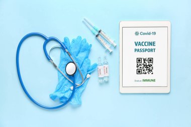 Elektronik bağışıklık pasaportu ekranda tablet bilgisayar, tıbbi eldivenler, steteskop ve aşının renkleri
