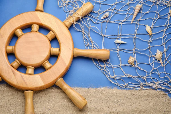 Dümen, kum, deniz kabukları ve arkaplanda ağ