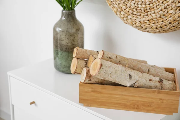 Yakacak odun ve vazo dolu bir kutu, ışık duvarının yanında.