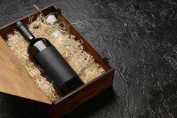 Box with bottle of wine on dark background
