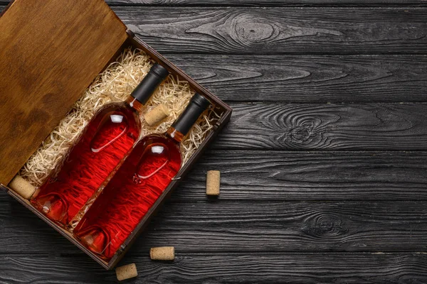 Box with bottles of wine on dark wooden background