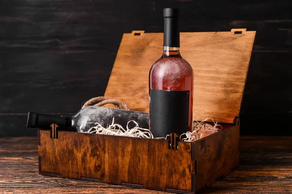 Box with bottles of wine on wooden background