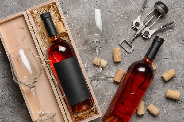 Arkaplanda şarap, bardak ve tirbuşon şişeleri olan bir kutu.