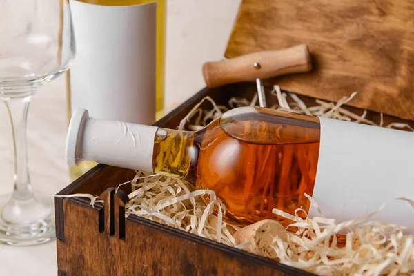 Box with bottles of wine, corkscrew and glass on marble background, closeup