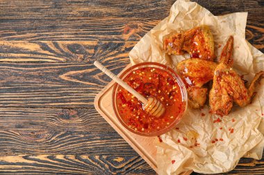 Lezzetli kızarmış tavuk kanatları ve ahşap arka planda sıcak bal.