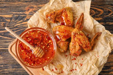 Lezzetli kızarmış tavuk kanatları ve ahşap arka planda sıcak bal.