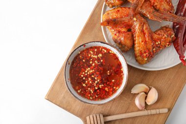 Lezzetli kızarmış tavuk kanatları, sarımsak ve sıcak bal, açık ahşap arka planda.