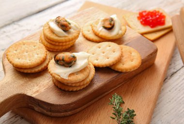 Hafif ahşap arka planda peynirli ve midyeli lezzetli krakerler, yakın plan.