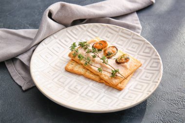 Koyu arkaplanda lezzetli krakerler olan tabak.