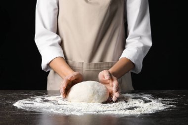 Kadın koyu arkaplanda hamur hazırlıyor