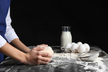 Koyu arka planda hamur yoğuran kadın