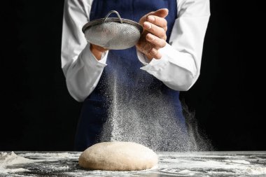 Kadın koyu arkaplanda hamuru süzüyor.