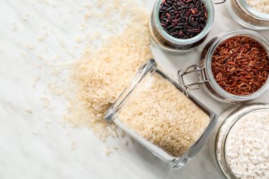 Açık arkaplanda farklı tipte çiğ pirinç bulunan kavanozlar