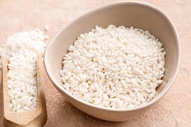 Arkaplanda çiğ pirinçli kase ve kepçe, yakın plan.