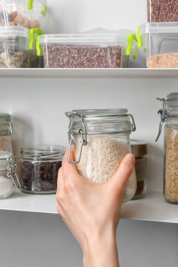 Mutfakta çiğ pirinçli kavanoz tutan kadın.