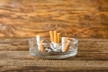 Ahşap arka planda sigaralı kül tablası