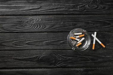 Kül tablası ve sigara koyu ahşap arka planda.