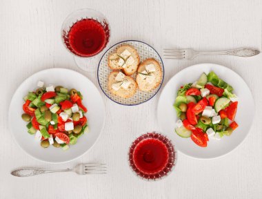 Taze Yunan salatalı tabaklar ve arka planda bir bardak şarap.