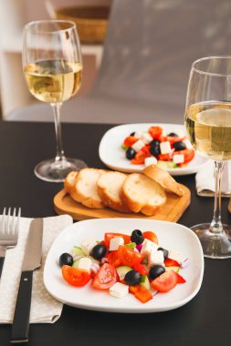 Restorandaki masada taze Yunan salatası ve bir bardak şarap.